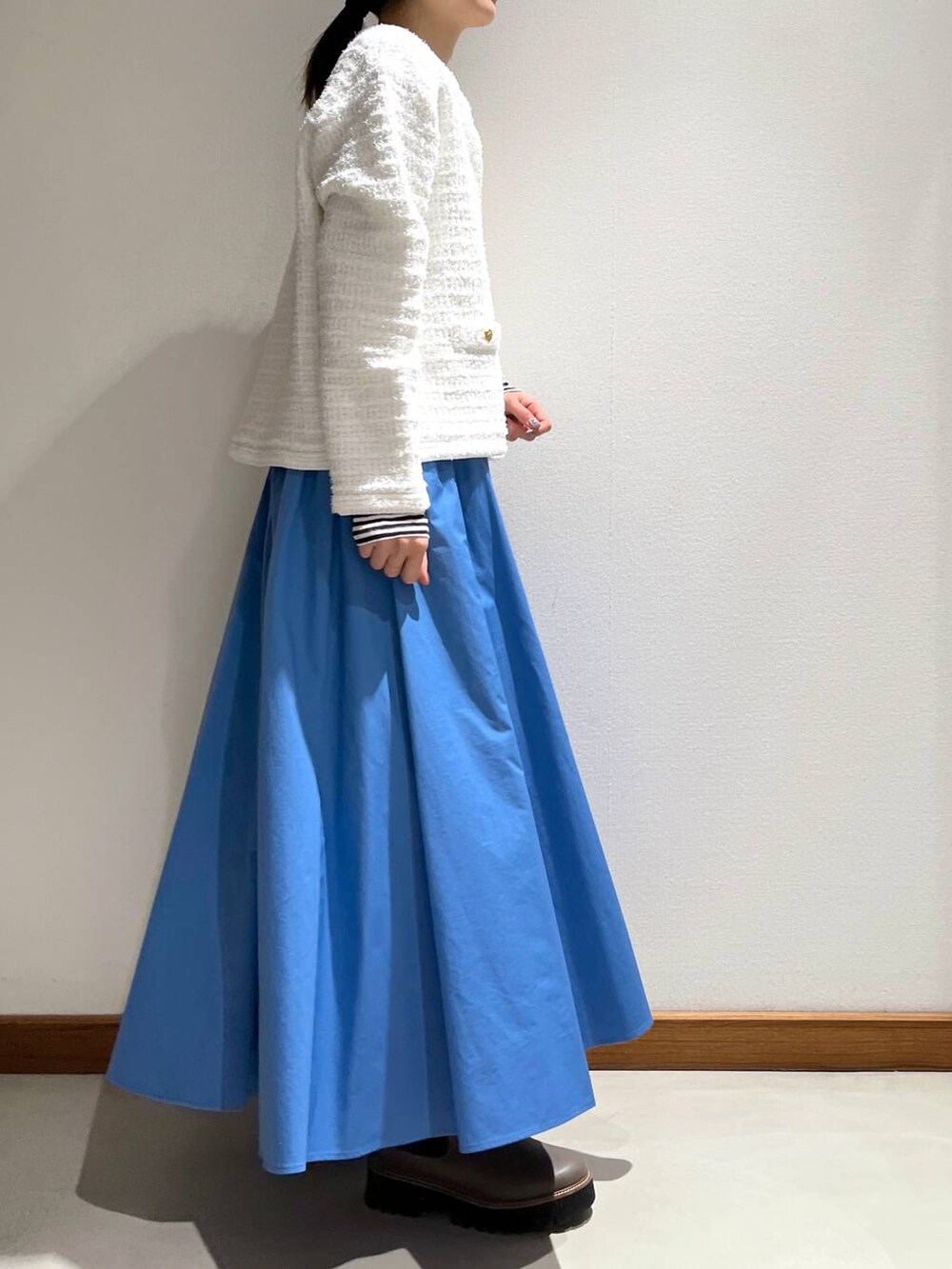 ベージュ系のブーツ、ブルー系のスカート、ホワイト系のカーディガン/ボレロを着用したレディースの冬コーディネートの4枚目の写真