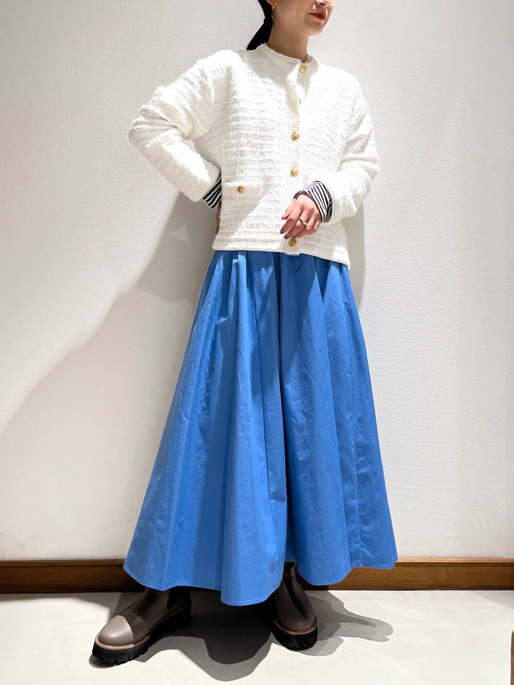 ベージュ系のブーツ、ブルー系のスカート、ホワイト系のカーディガン/ボレロを着用したレディースの冬コーディネートの3枚目の写真