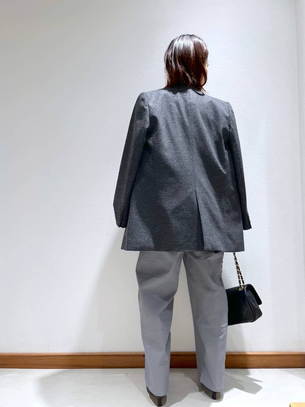 ブラック系のニット/セーター、ブラック系のブーツ、グレー系のノーカラージャケットを着用したレディースの秋コーディネートの4枚目の写真