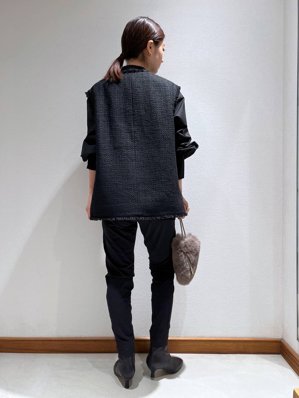 ブラック系のブーツ、ブラック系のスラックス、ブラック系のベストを着用したレディースの冬コーディネートの5枚目の写真