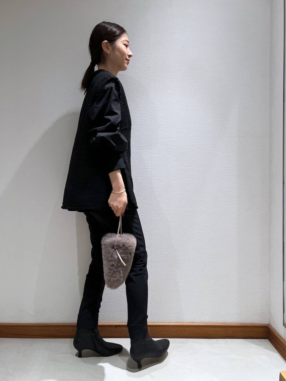 ブラック系のブーツ、ブラック系のスラックス、ブラック系のベストを着用したレディースの冬コーディネートの4枚目の写真
