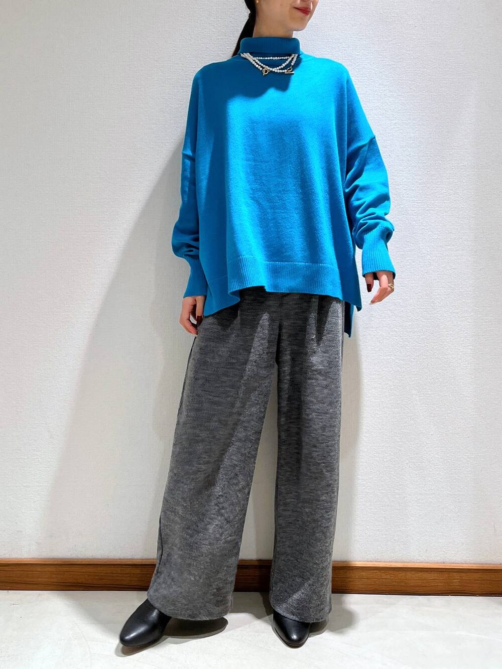 ブラック系のブーツ、グレー系のスラックス、ブルー系のニット/セーターを着用したレディースの冬コーディネートの2枚目の写真