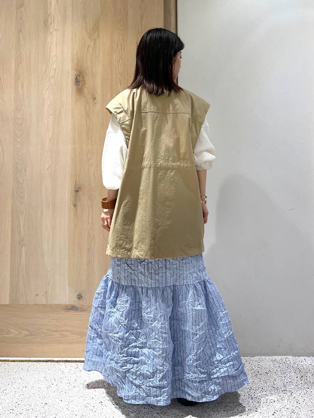 ベージュ系のブルゾン、ホワイト系のニット/セーター、ブルー系のスカートを着用したレディースの春コーディネートの4枚目の写真