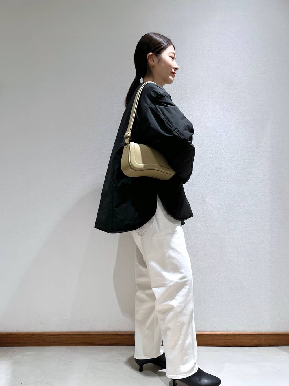 ブラック系のブーツ、ベージュ系のショルダーバッグ、ホワイト系のニット/セーターを着用したレディースの冬コーディネートの3枚目の写真