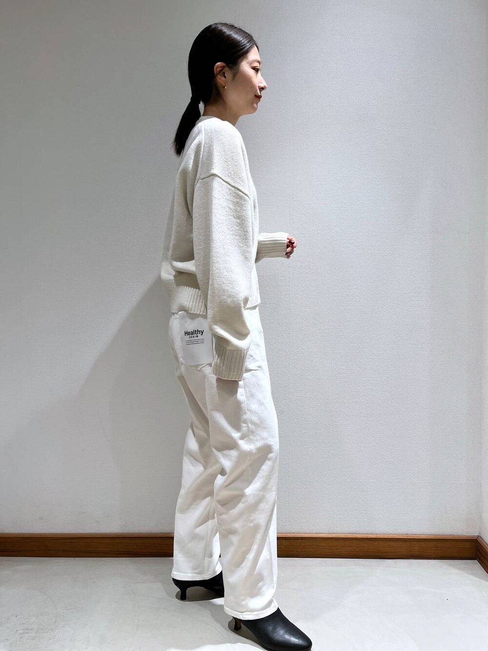 ブラック系のブーツ、ベージュ系のショルダーバッグ、ホワイト系のニット/セーターを着用したレディースの冬コーディネートの7枚目の写真