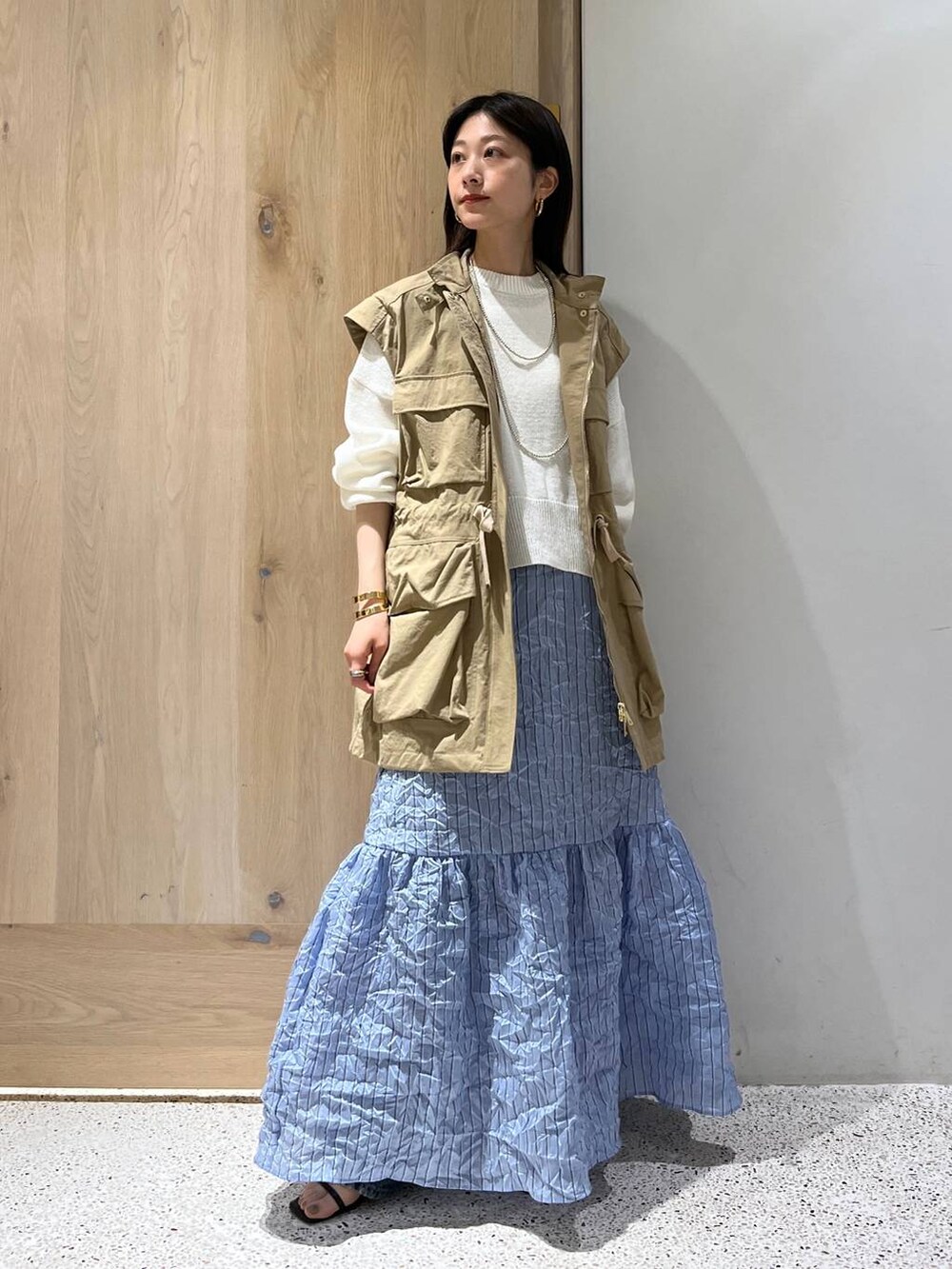 ベージュ系のブルゾン、ホワイト系のニット/セーター、ブルー系のスカートを着用したレディースの春コーディネートの2枚目の写真