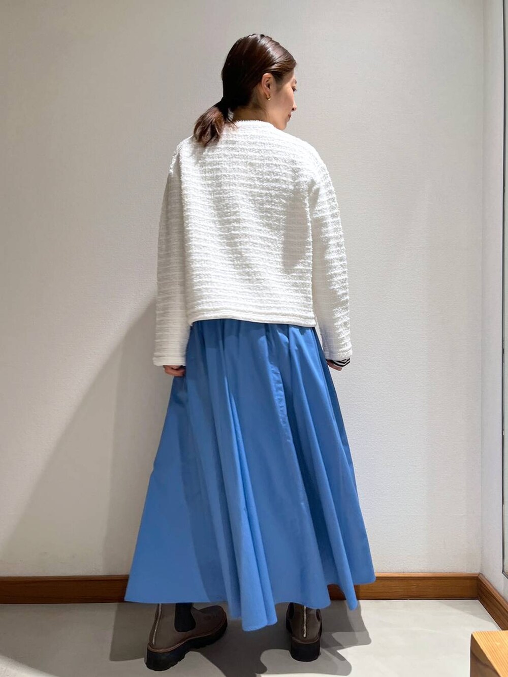 ベージュ系のブーツ、ブルー系のスカート、ホワイト系のカーディガン/ボレロを着用したレディースの冬コーディネートの5枚目の写真