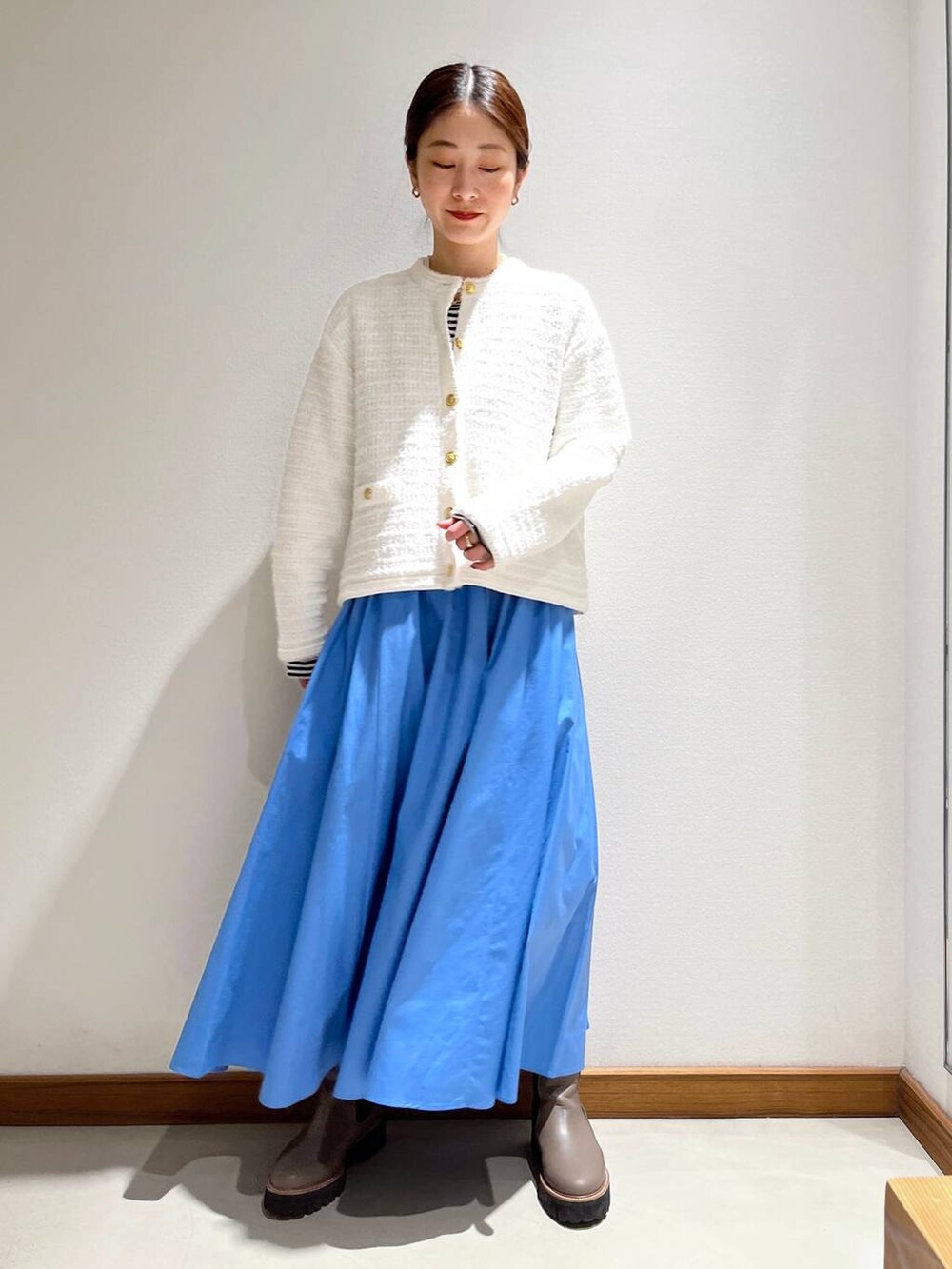 ベージュ系のブーツ、ブルー系のスカート、ホワイト系のカーディガン/ボレロを着用したレディースの冬コーディネートの2枚目の写真