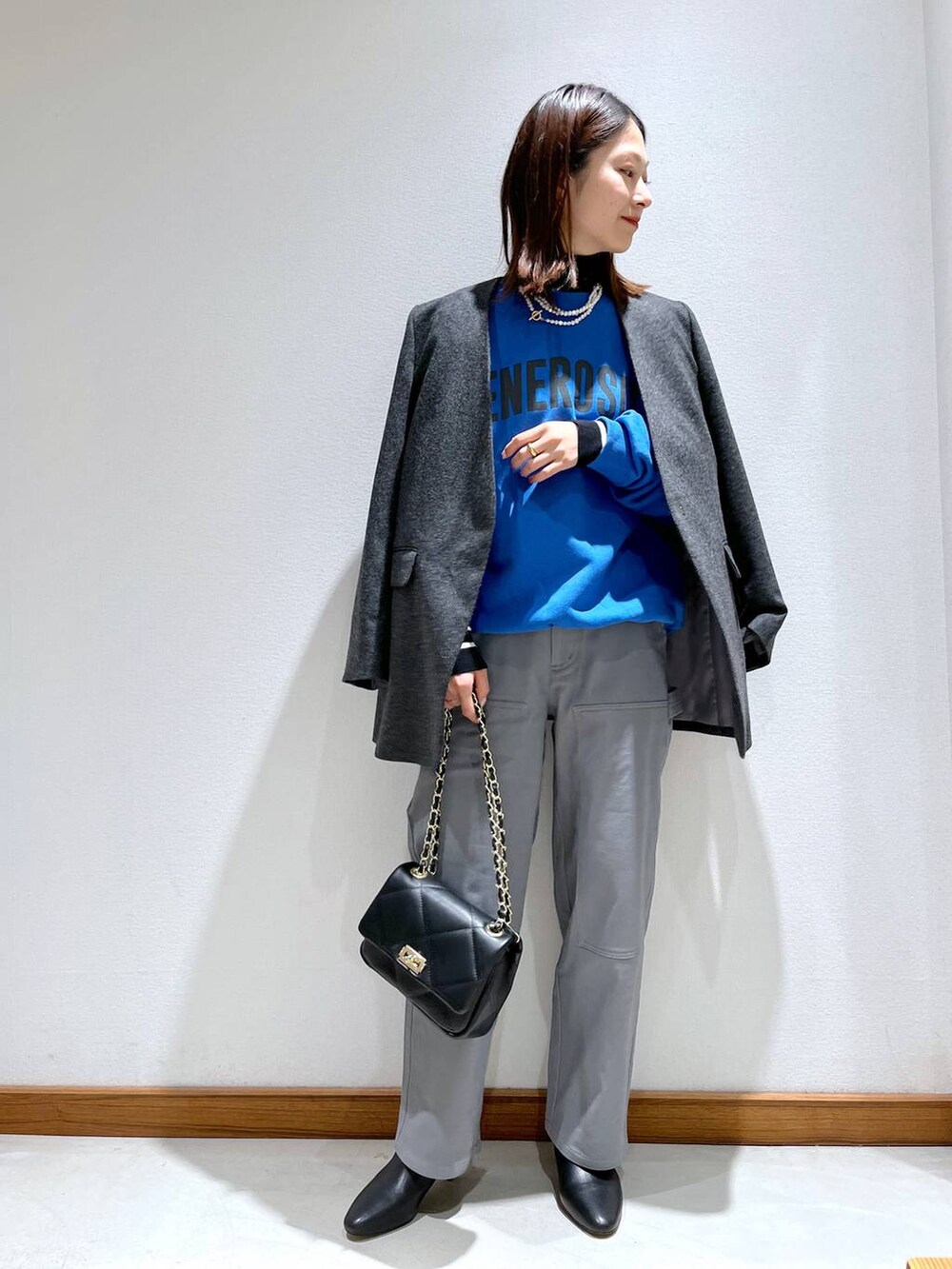 ブラック系のニット/セーター、ブラック系のブーツ、グレー系のノーカラージャケットを着用したレディースの秋コーディネートの2枚目の写真