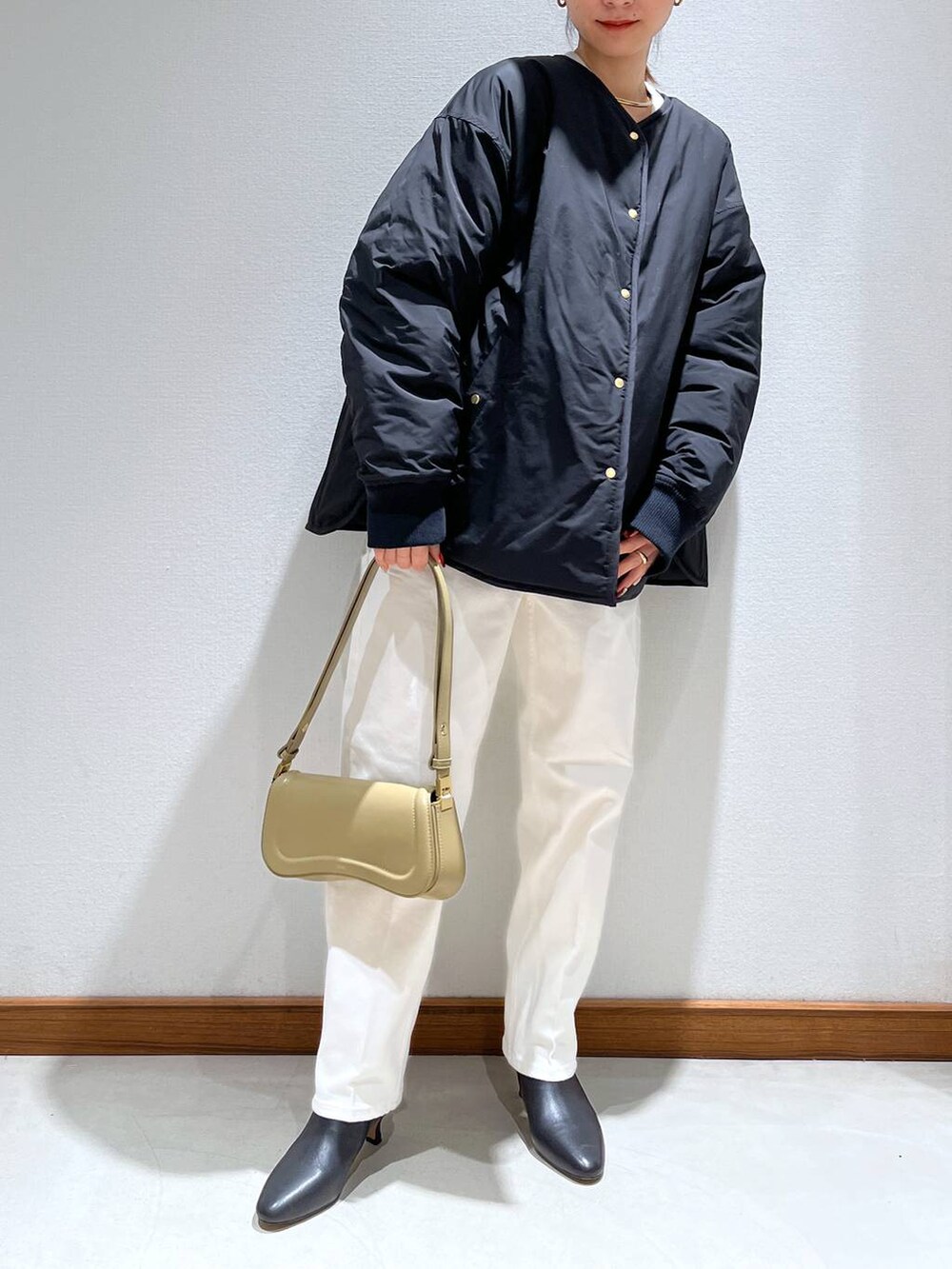 ブラック系のブーツ、ベージュ系のショルダーバッグ、ホワイト系のニット/セーターを着用したレディースの冬コーディネートの2枚目の写真