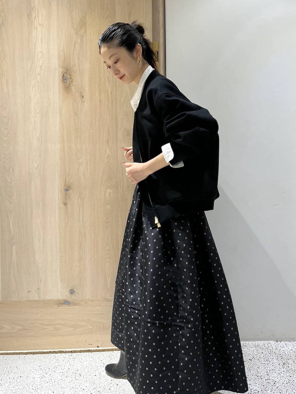 ブラック系のスカート、ブラック系のブルゾン、ホワイト系のシャツ/ブラウスを着用したレディースの秋コーディネートの4枚目の写真