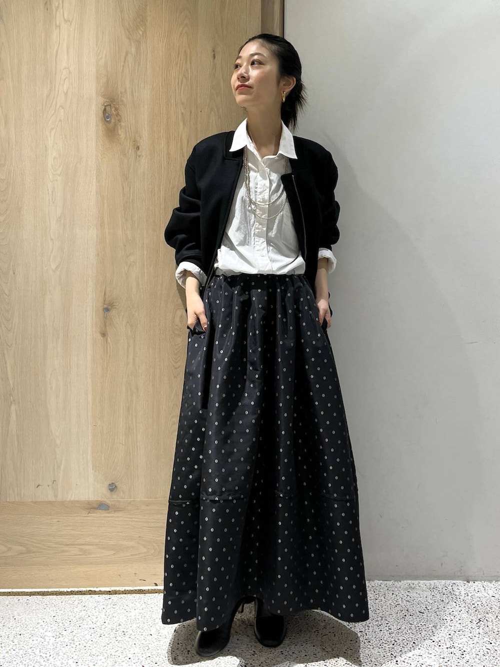 ブラック系のスカート、ブラック系のブルゾン、ホワイト系のシャツ/ブラウスを着用したレディースの秋コーディネートの3枚目の写真