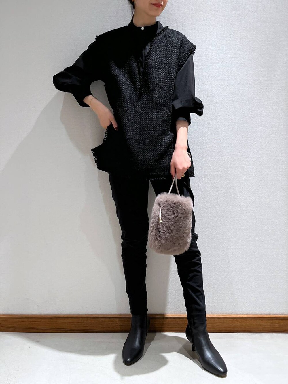 ブラック系のブーツ、ブラック系のスラックス、ブラック系のベストを着用したレディースの冬コーディネートの2枚目の写真