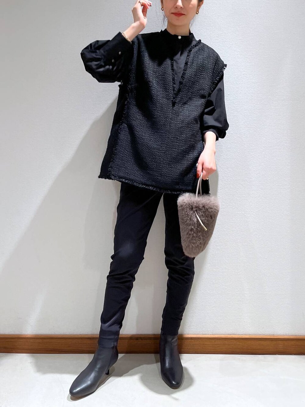 ブラック系のブーツ、ブラック系のスラックス、ブラック系のベストを着用したレディースの冬コーディネートの3枚目の写真