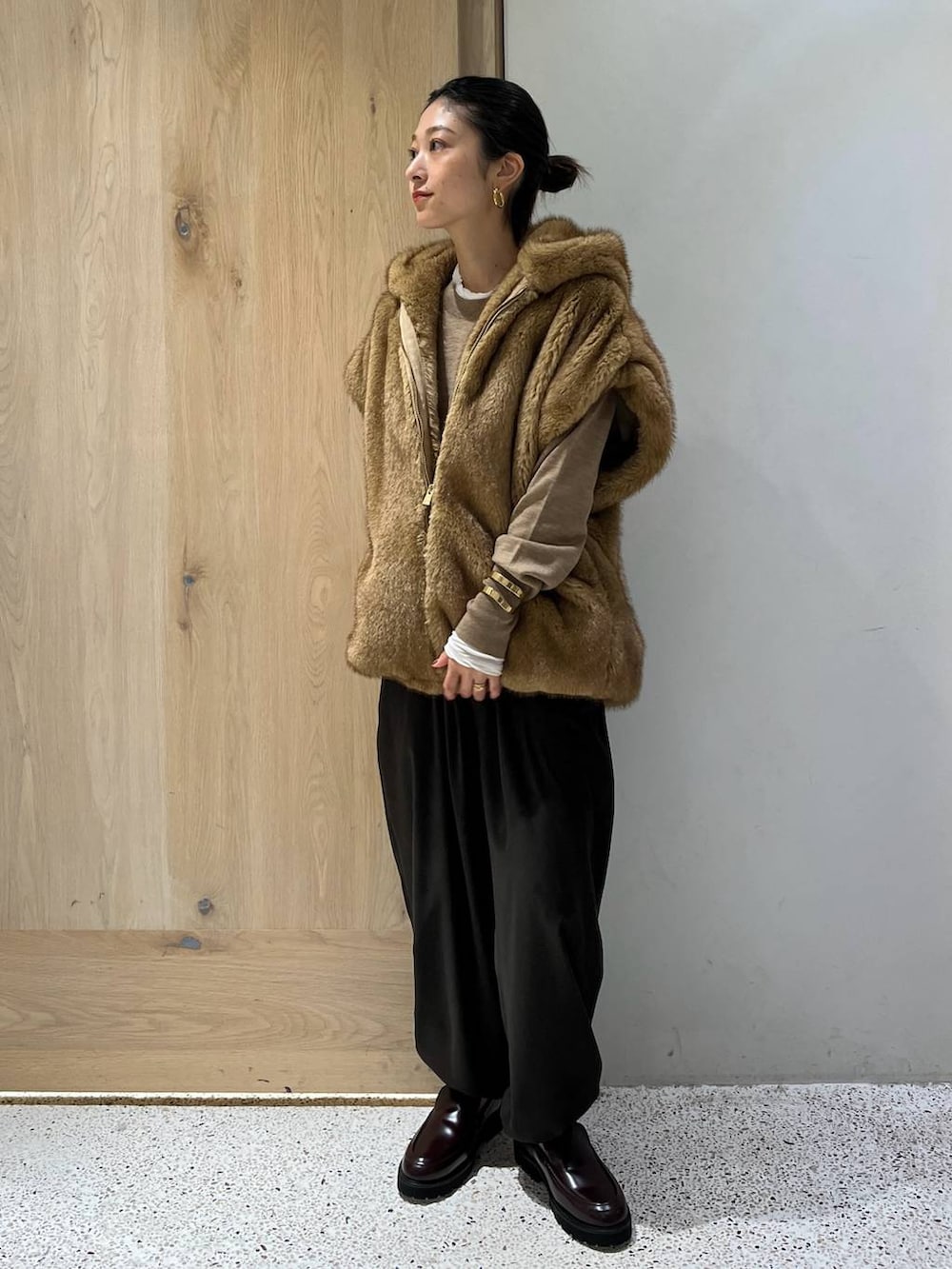 ホワイト系のTシャツ/カットソー、ベージュ系のベスト、ブラウン系のニット/セーターを着用したレディースの秋コーディネートの2枚目の写真