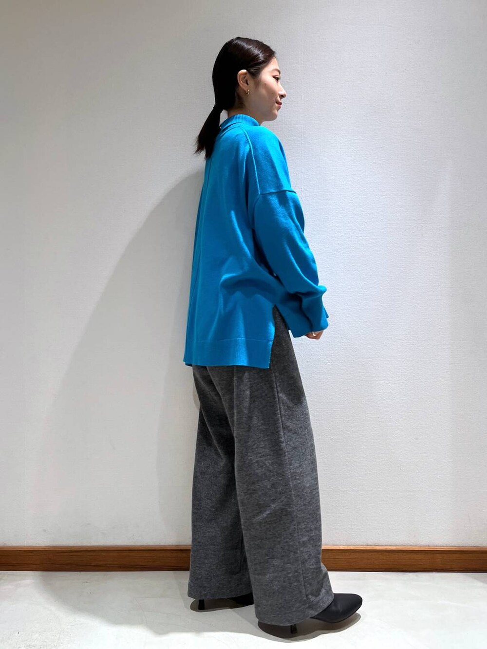 ブラック系のブーツ、グレー系のスラックス、ブルー系のニット/セーターを着用したレディースの冬コーディネートの3枚目の写真