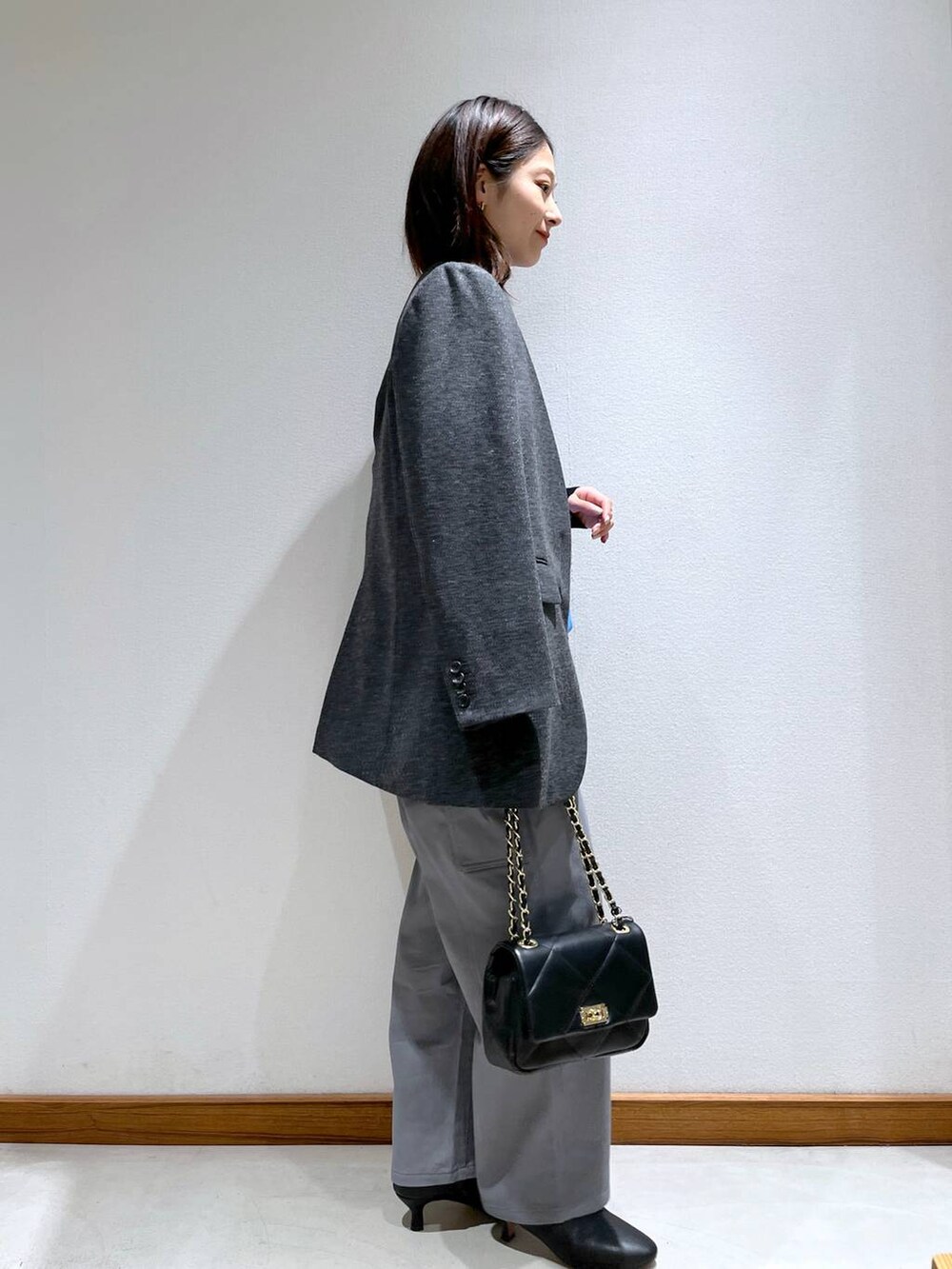 ブラック系のニット/セーター、ブラック系のブーツ、グレー系のノーカラージャケットを着用したレディースの秋コーディネートの3枚目の写真