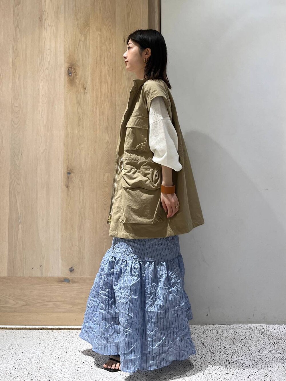 ベージュ系のブルゾン、ホワイト系のニット/セーター、ブルー系のスカートを着用したレディースの春コーディネートの3枚目の写真