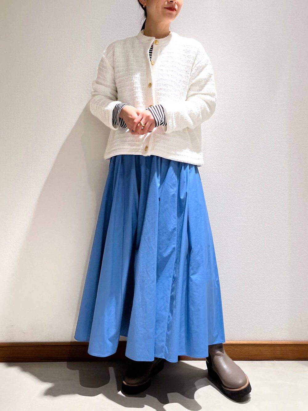 ベージュ系のブーツ、ブルー系のスカート、ホワイト系のカーディガン/ボレロを着用したレディースの冬コーディネートの6枚目の写真