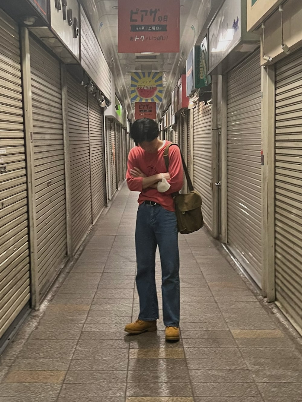 ブルー系のデニムパンツ、ベージュ系のブーツ、グリーン系のメッセンジャーバッグを着用したメンズの秋コーディネートの2枚目の写真