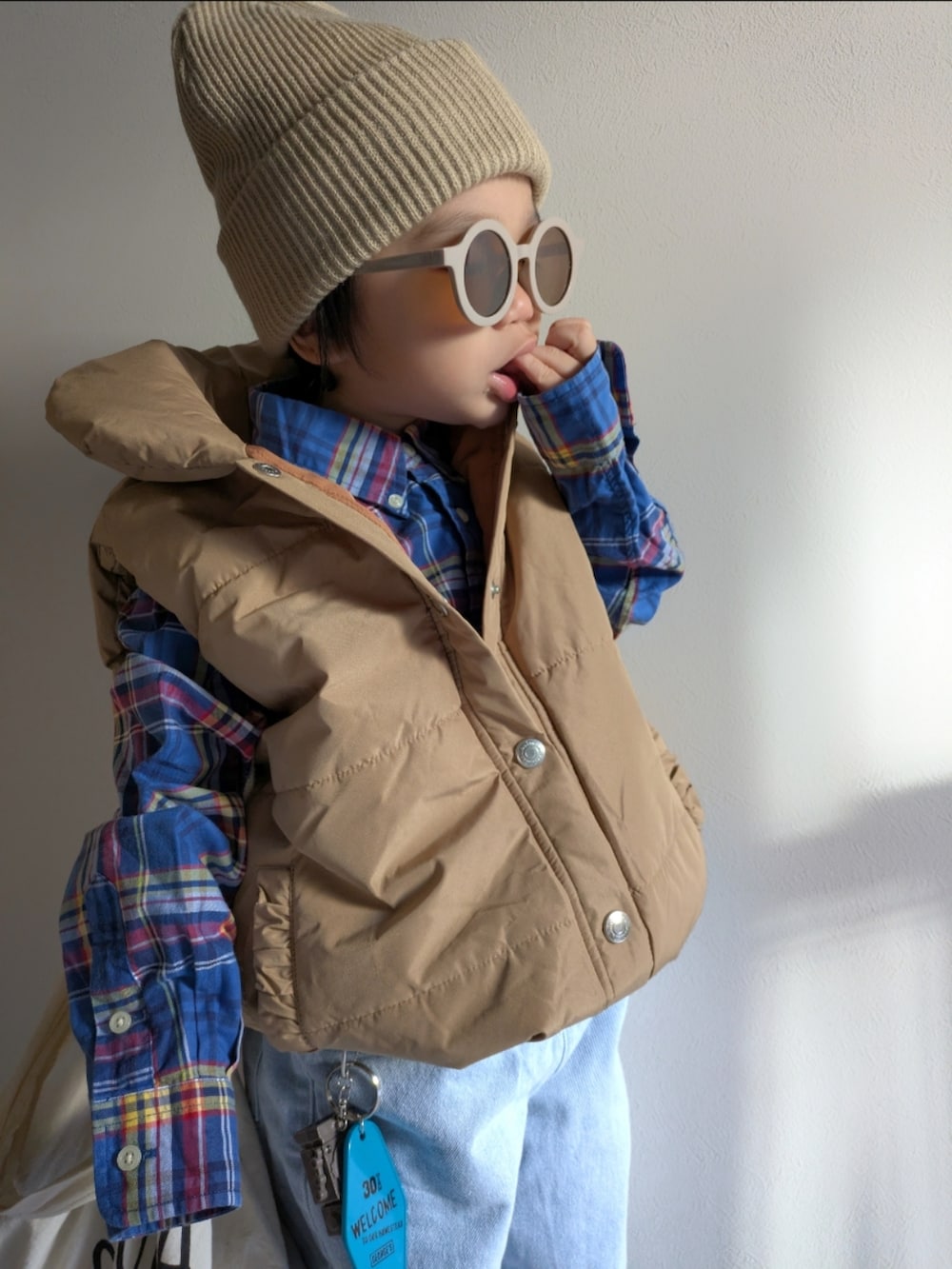 ブルー系のデニムパンツ、レッド系のスニーカー、ベージュ系のニットキャップ/ビーニーを着用したキッズの冬コーディネートの2枚目の写真