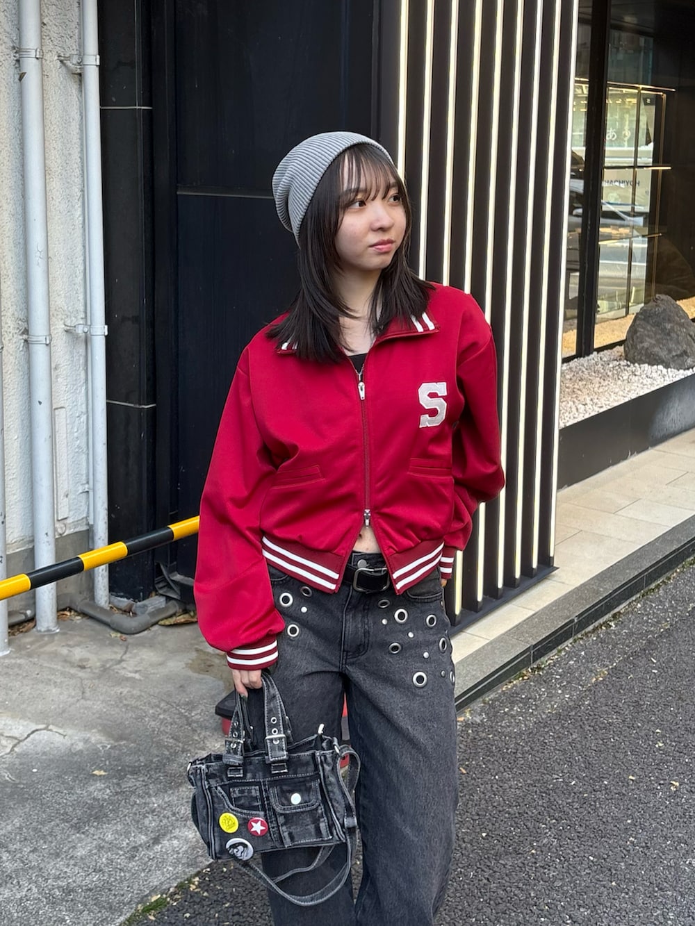 レッド系のブルゾン、ブラック系のデニムパンツ、ブラック系のショルダーバッグを着用したレディースの冬コーディネートの2枚目の写真