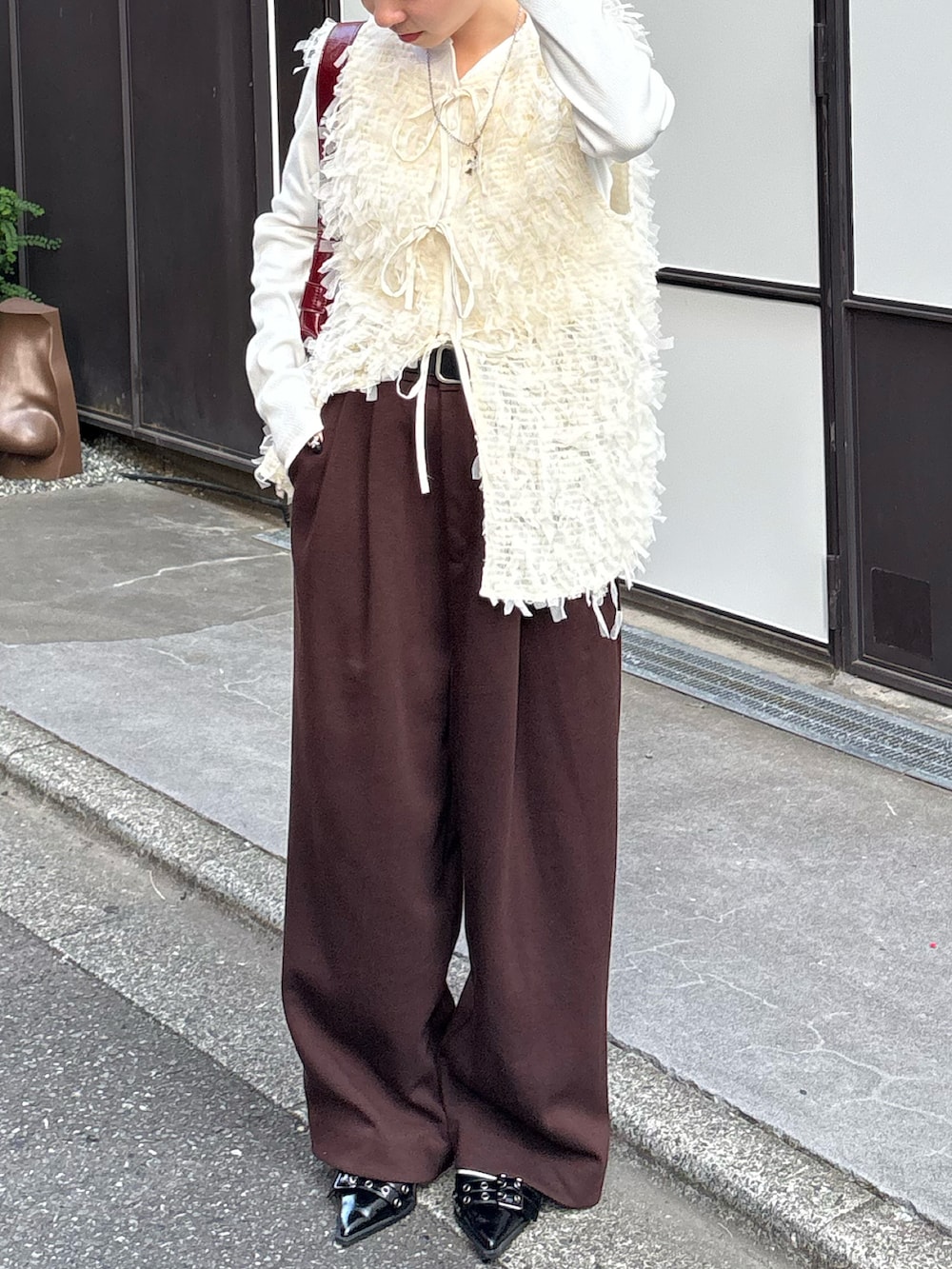 ホワイト系のTシャツ/カットソー、ホワイト系のベスト、レッド系のショルダーバッグを着用したレディースの秋コーディネートの3枚目の写真