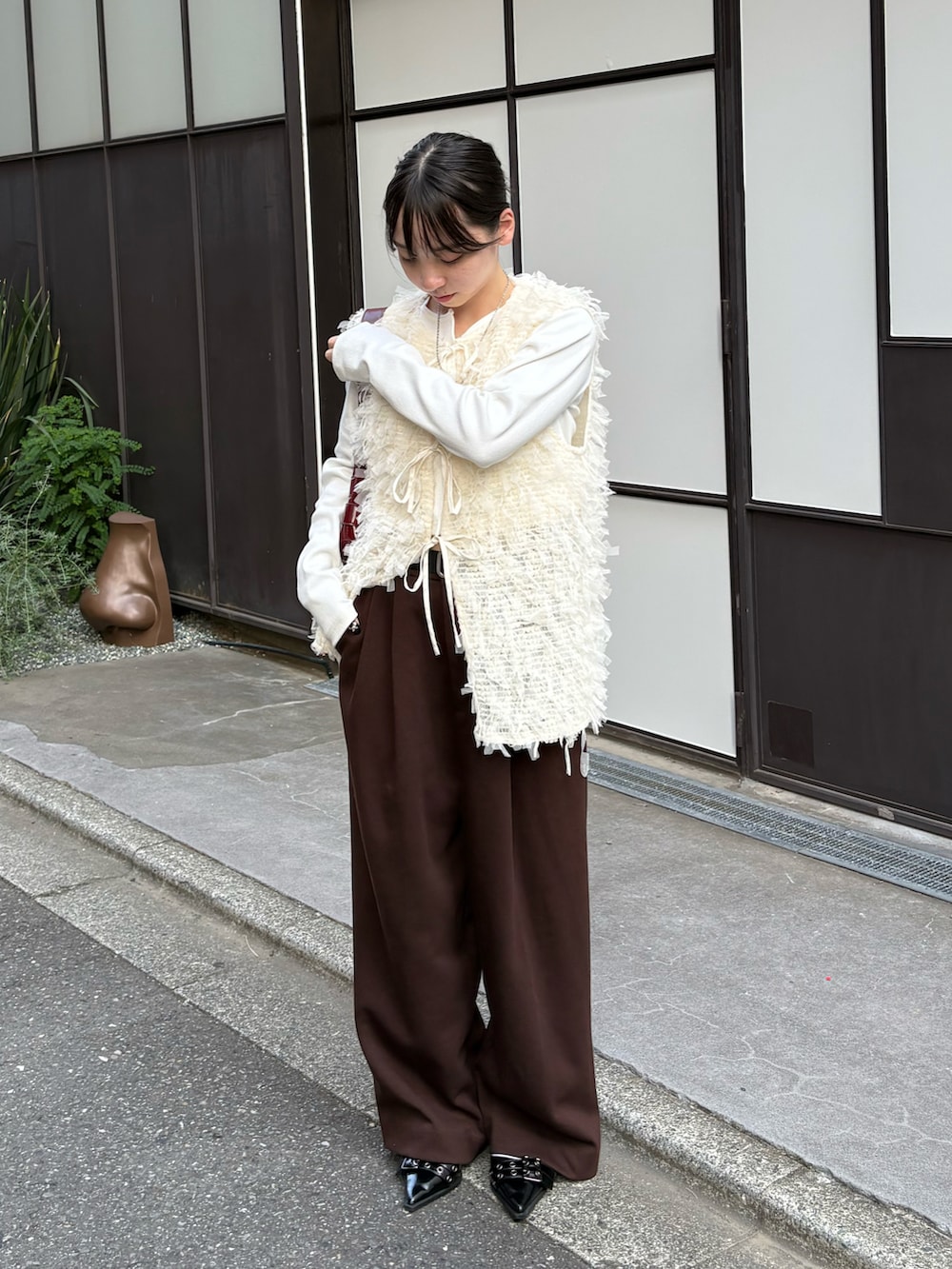 ホワイト系のTシャツ/カットソー、ホワイト系のベスト、レッド系のショルダーバッグを着用したレディースの秋コーディネートの2枚目の写真