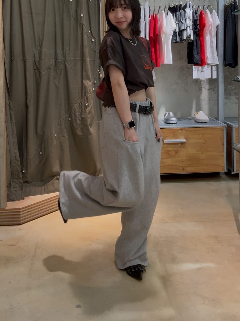 グレー系のスウェットパンツ、ブラウン系のTシャツ/カットソー、レッド系のショルダーバッグを着用したレディースの春コーディネートの2枚目の写真