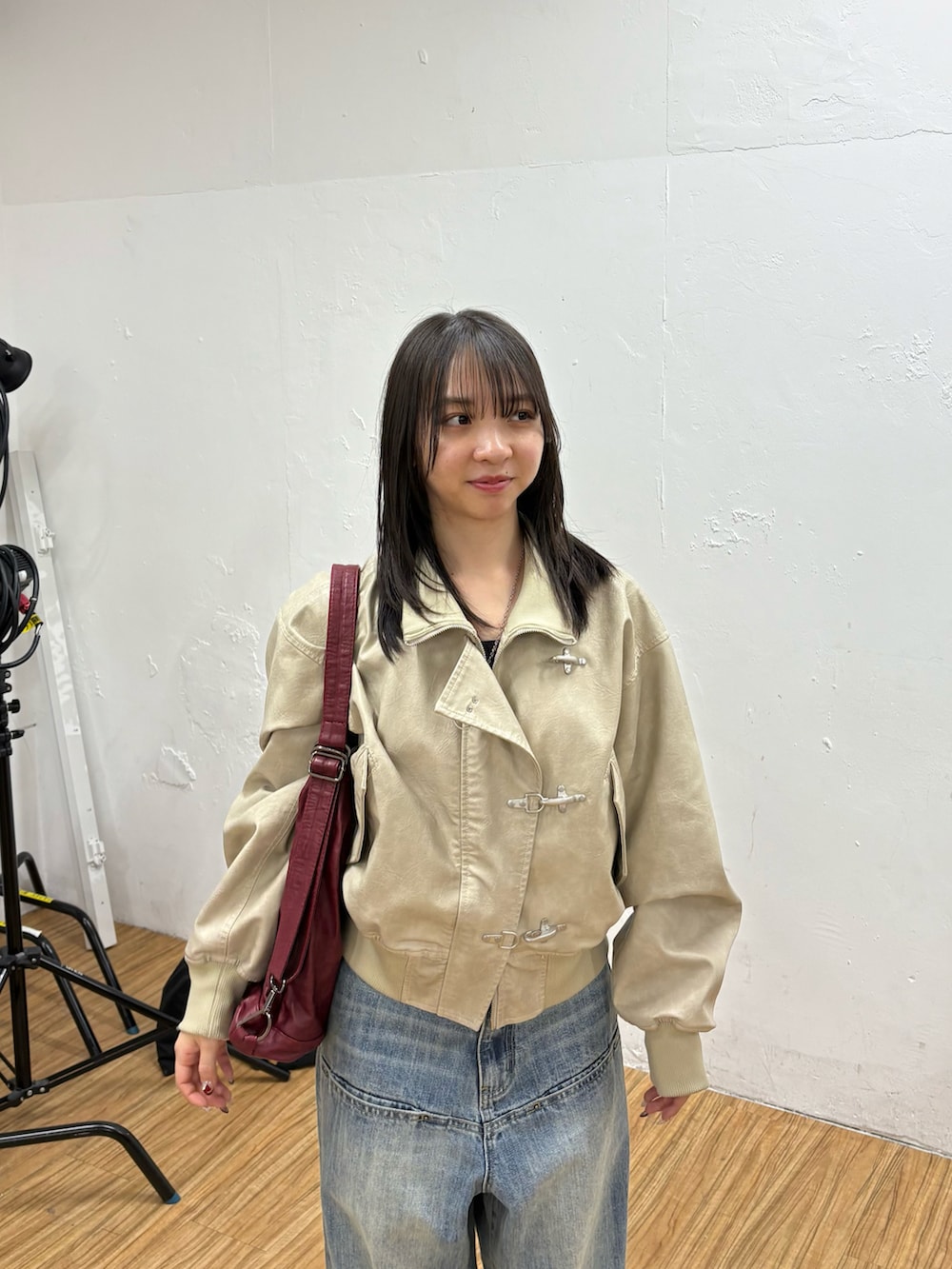 ホワイト系のブルゾン、ブルー系のデニムパンツ、ブラック系のパンプスを着用したレディースの冬コーディネートの2枚目の写真