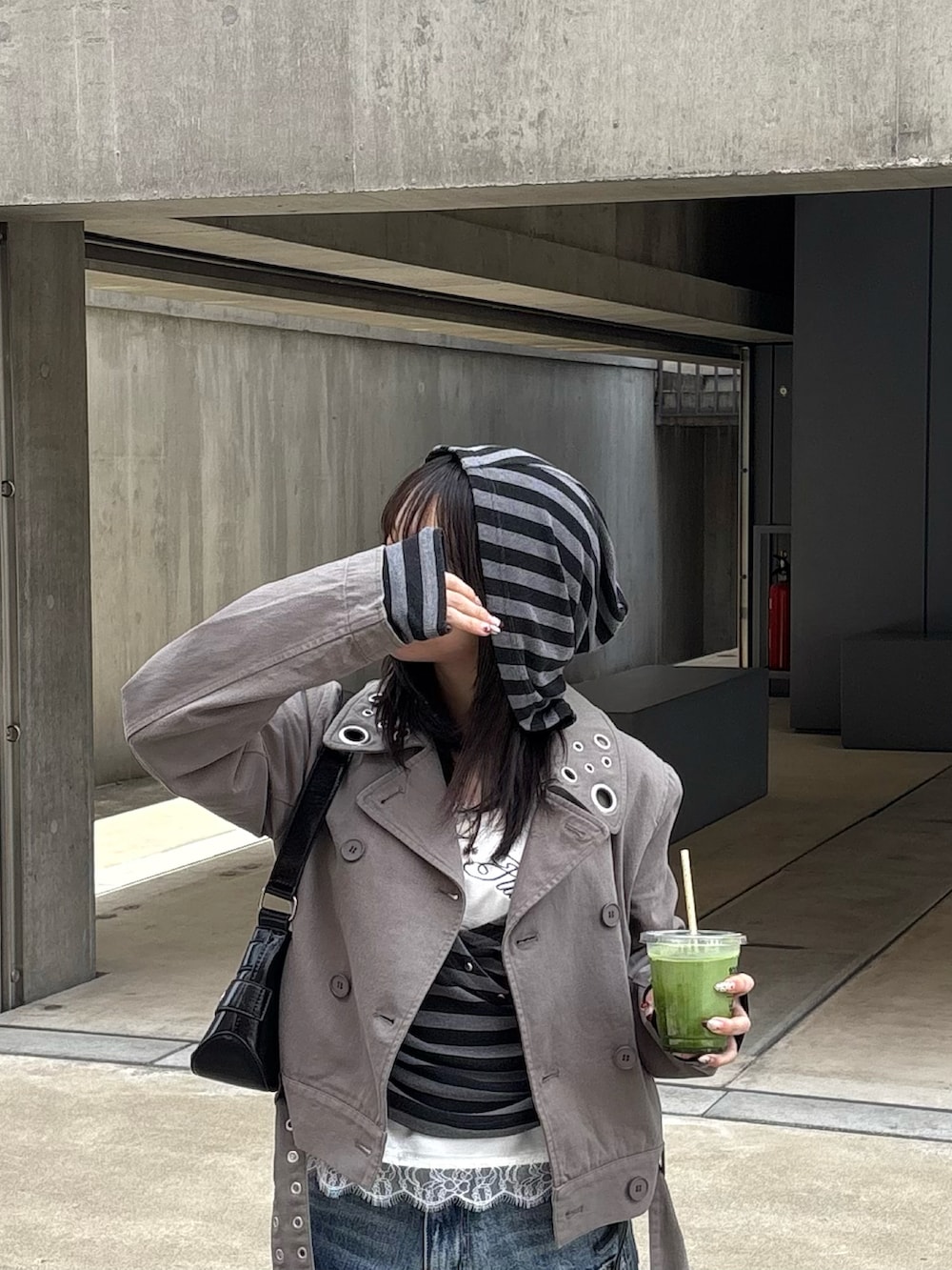 グレー系のピーコート、グレー系のパーカー、ホワイト系のキャミソールを着用したレディースの春コーディネートの2枚目の写真