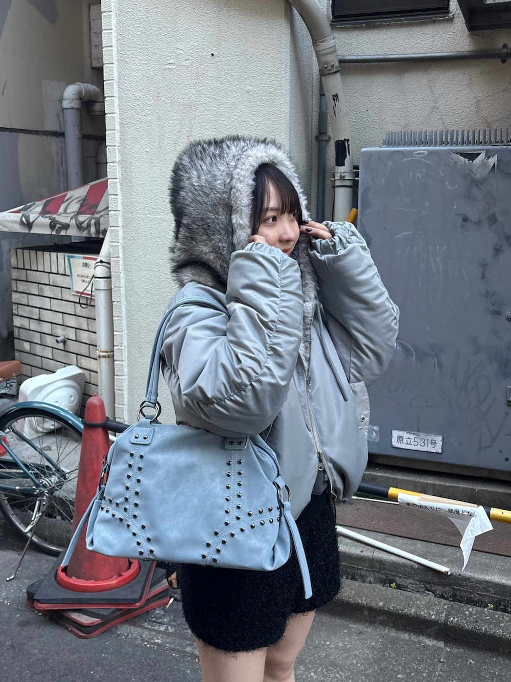 グレー系のブルゾン、ブルー系のショルダーバッグを着用したレディースの冬コーディネートの2枚目の写真