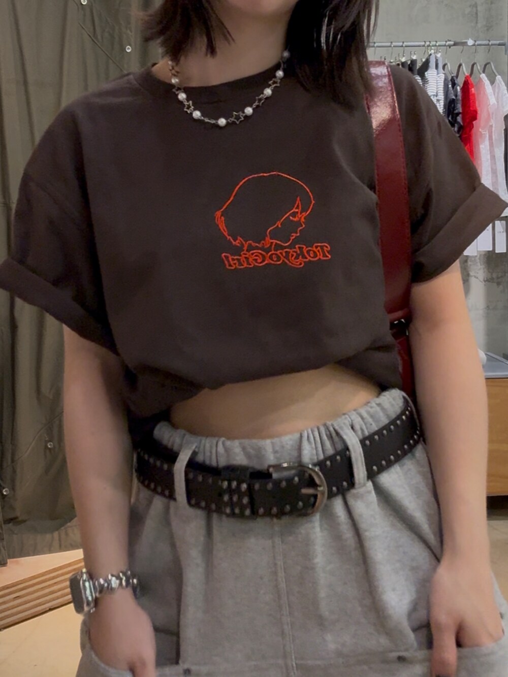 グレー系のスウェットパンツ、ブラウン系のTシャツ/カットソー、レッド系のショルダーバッグを着用したレディースの春コーディネートの3枚目の写真