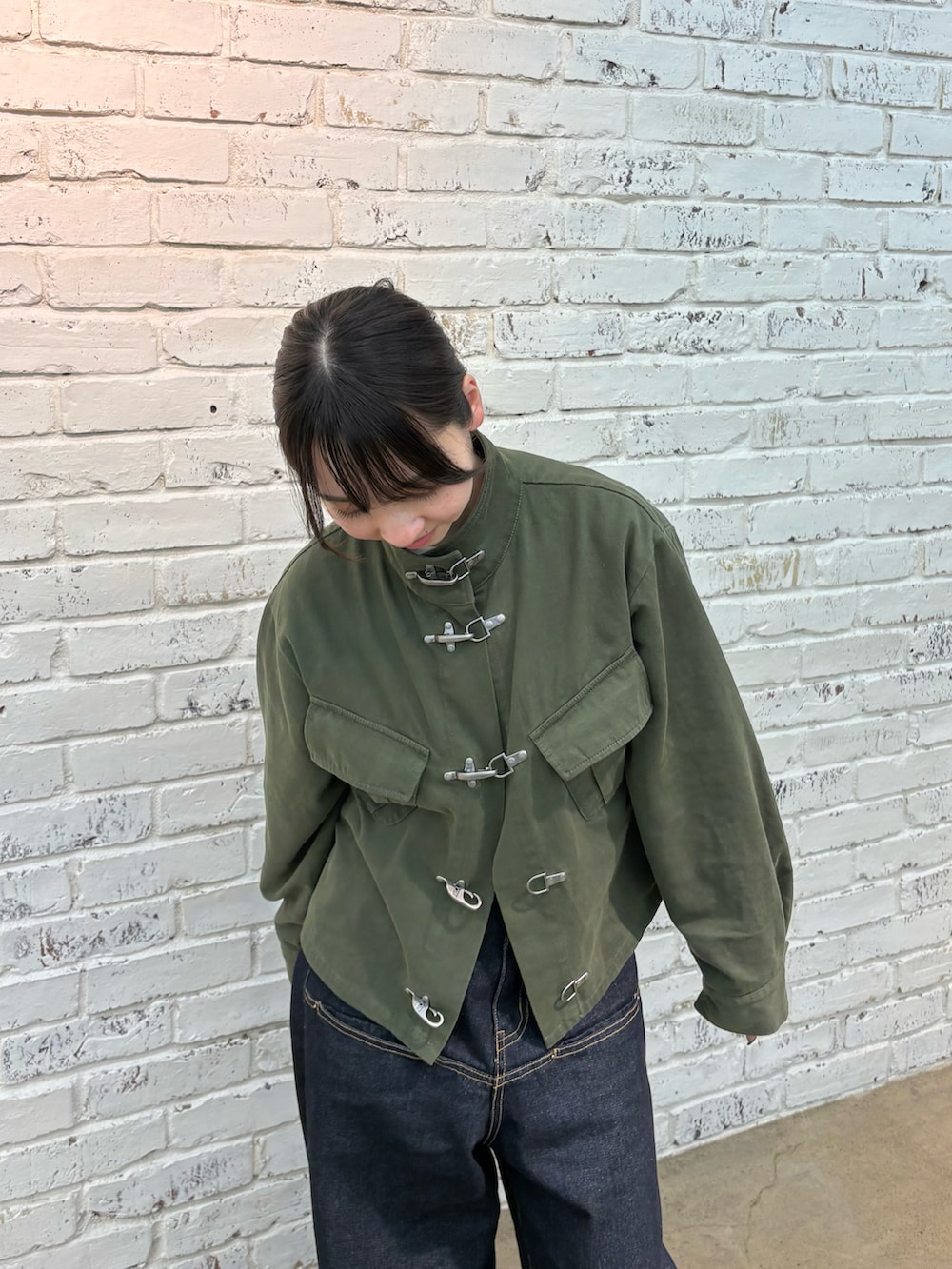 グリーン系のミリタリージャケット、ブルー系のデニムパンツを着用したレディースの冬コーディネートの2枚目の写真