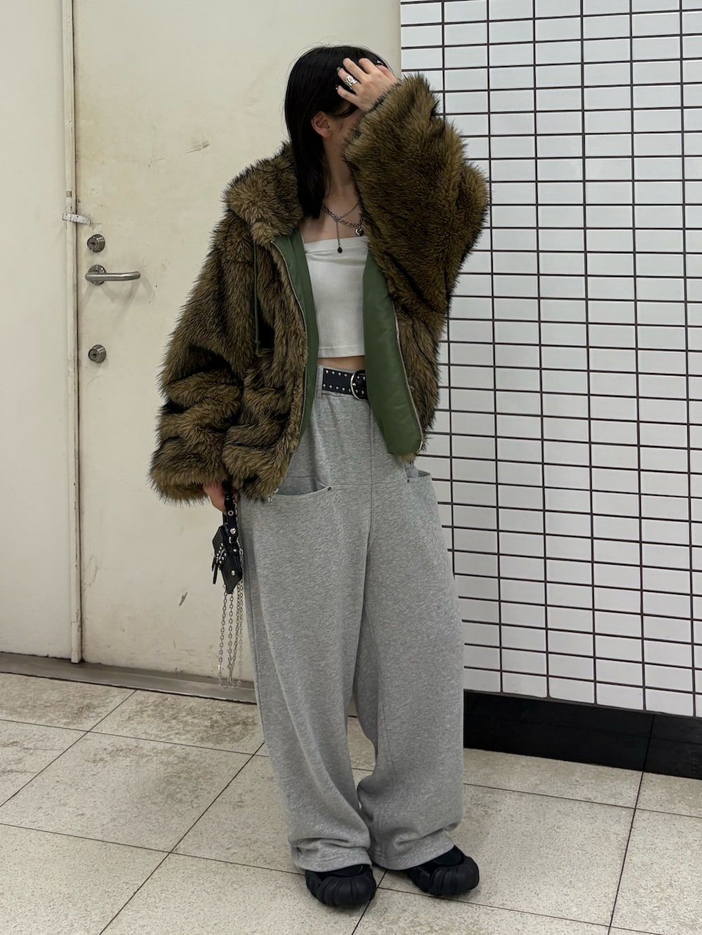 グレー系のスウェットパンツ、グリーン系のブルゾン、ブラック系のバッグを着用したレディースの秋コーディネートの2枚目の写真