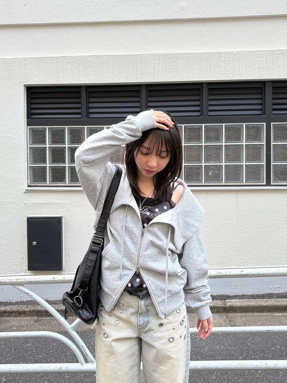 ブラック系のショルダーバッグ、ブルー系のデニムパンツ、グレー系のパーカーを着用したレディースの冬コーディネートの2枚目の写真