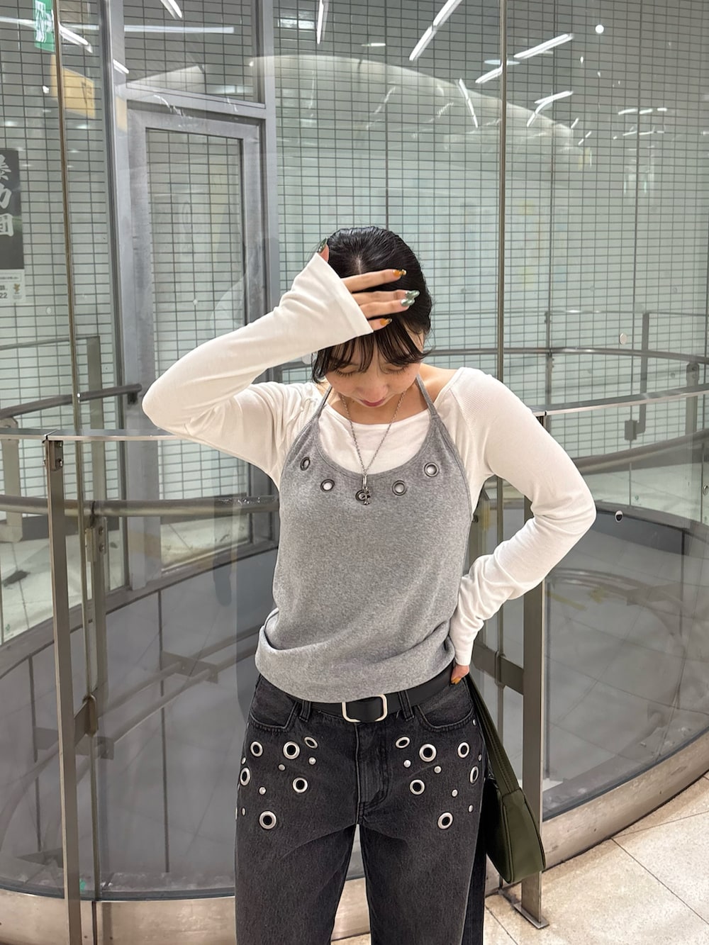 ブラック系のデニムパンツ、グレー系のTシャツ/カットソー、グリーン系のショルダーバッグを着用したレディースの冬コーディネートの2枚目の写真