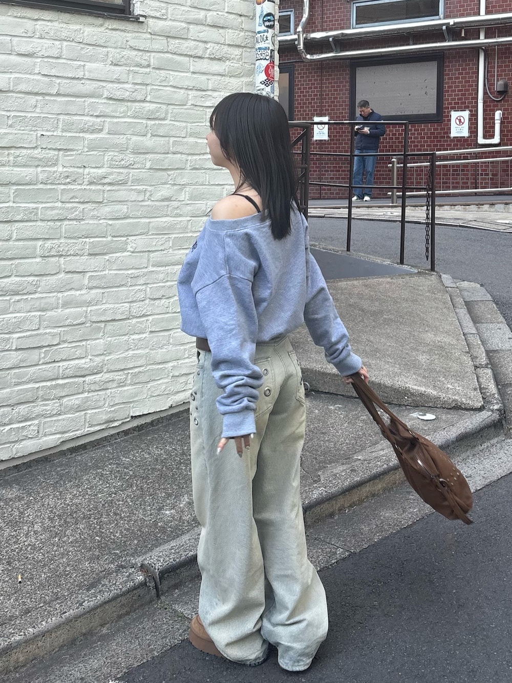 ブルー系のデニムパンツ、グレー系のスウェット、ブラウン系のショルダーバッグを着用したレディースの冬コーディネートの2枚目の写真