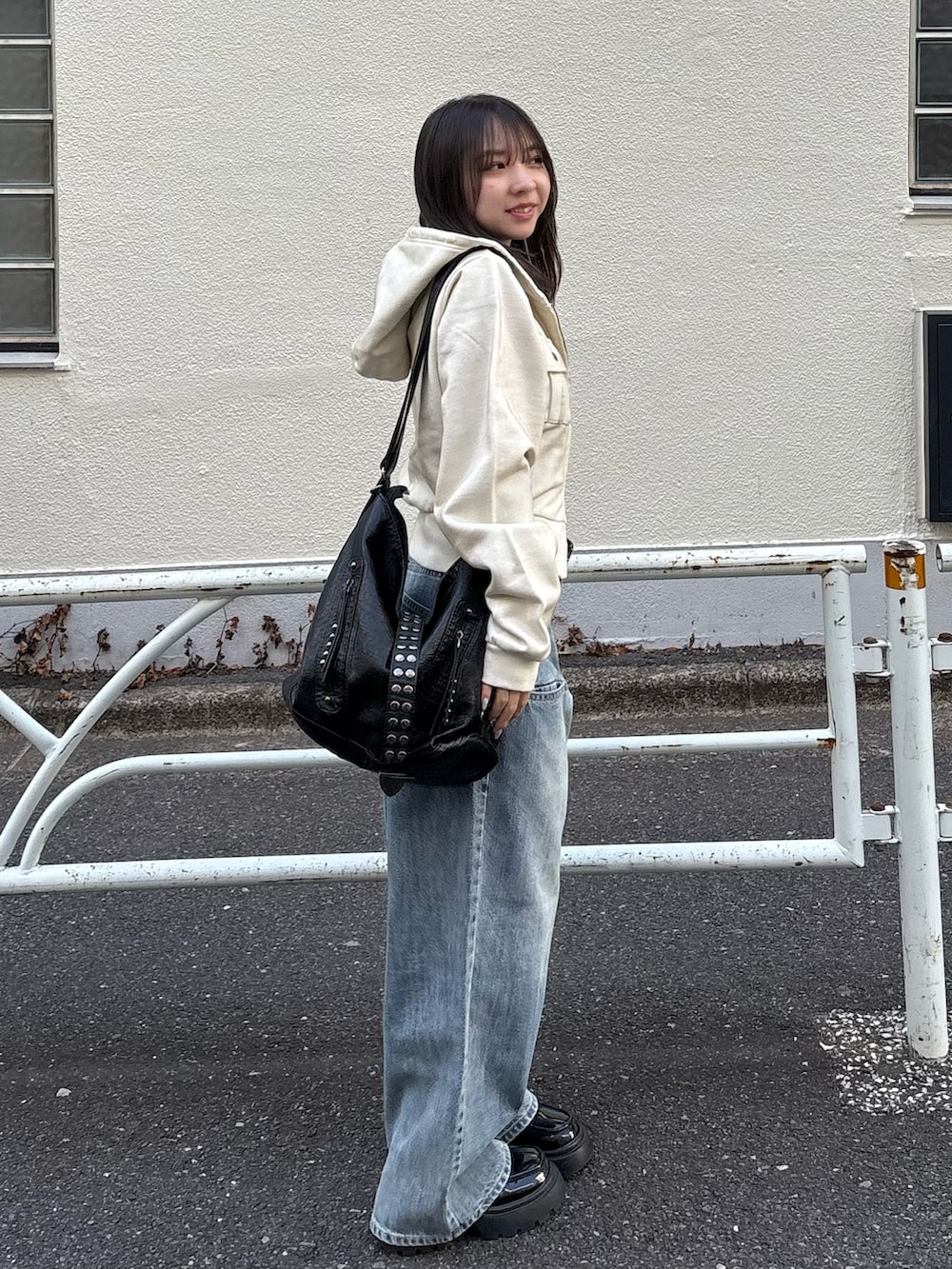 ブルー系のデニムパンツ、ブラック系のショルダーバッグを着用したレディースの冬コーディネートの2枚目の写真