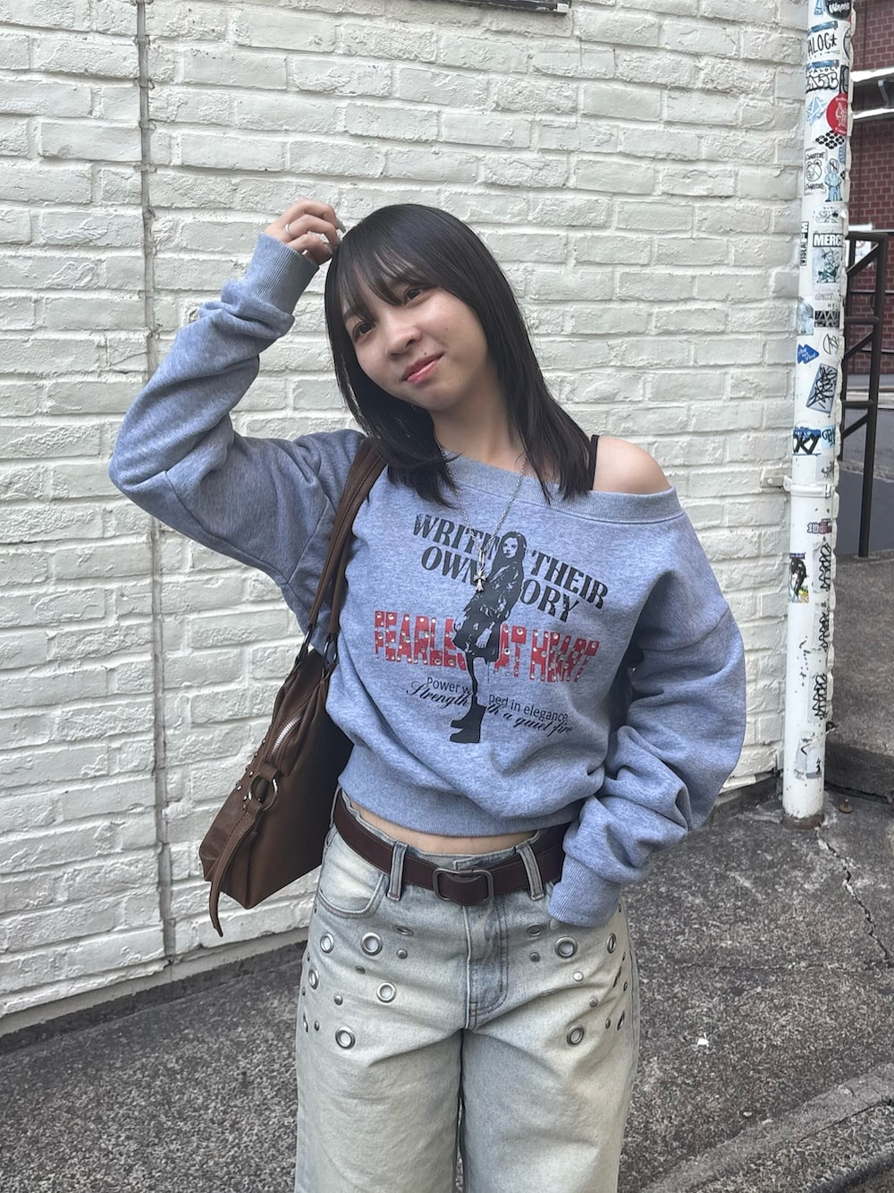 ブルー系のデニムパンツ、グレー系のスウェット、ブラウン系のショルダーバッグを着用したレディースの冬コーディネートの3枚目の写真