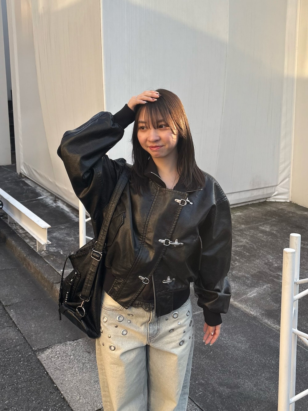 ブラック系のブルゾン、ブルー系のデニムパンツ、ブラック系のショルダーバッグを着用したレディースの冬コーディネートの2枚目の写真