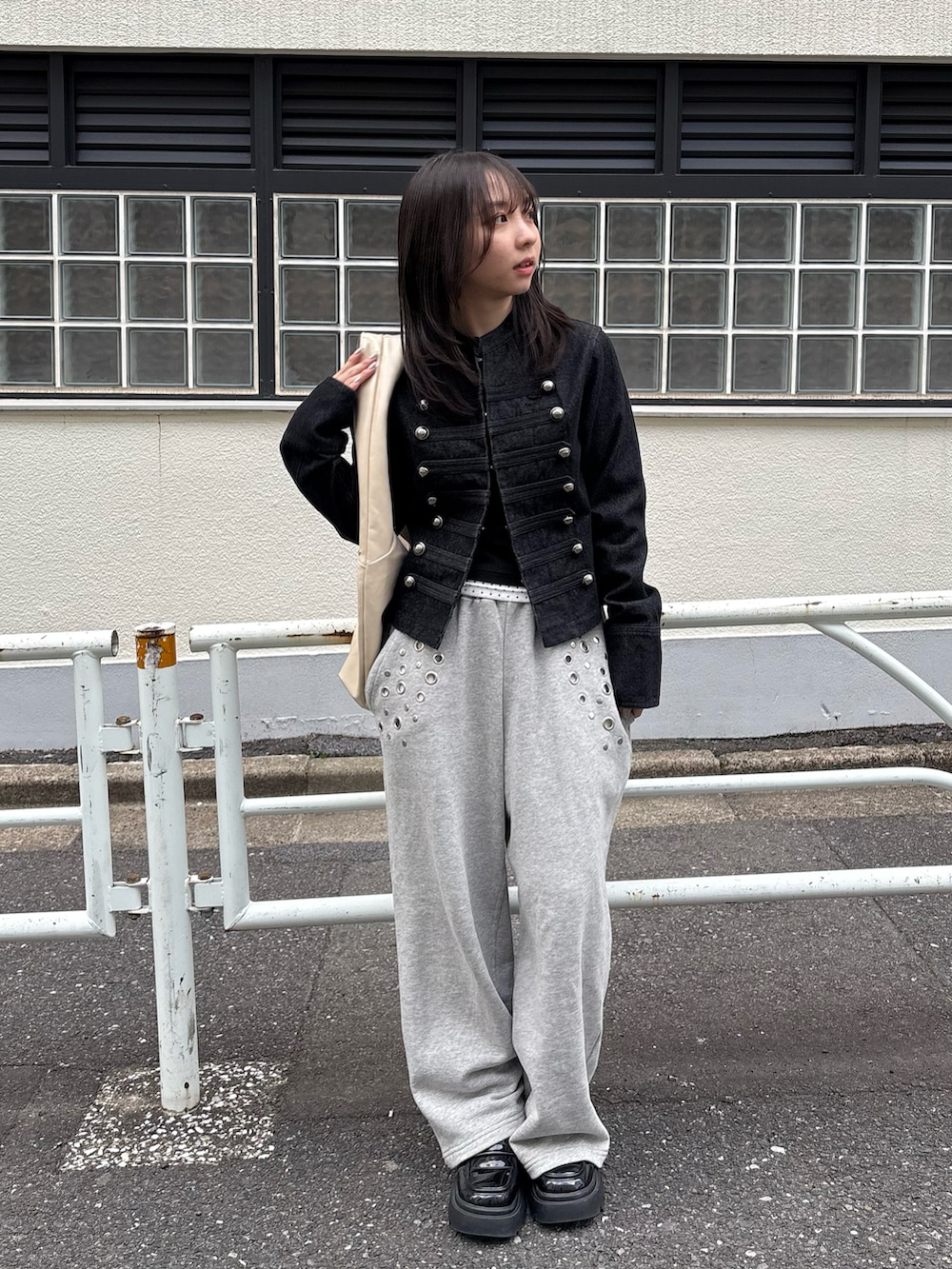 ブラック系のデニムジャケット、ブラック系のTシャツ/カットソー、グレー系のスウェットパンツを着用したレディースの春コーディネートの2枚目の写真