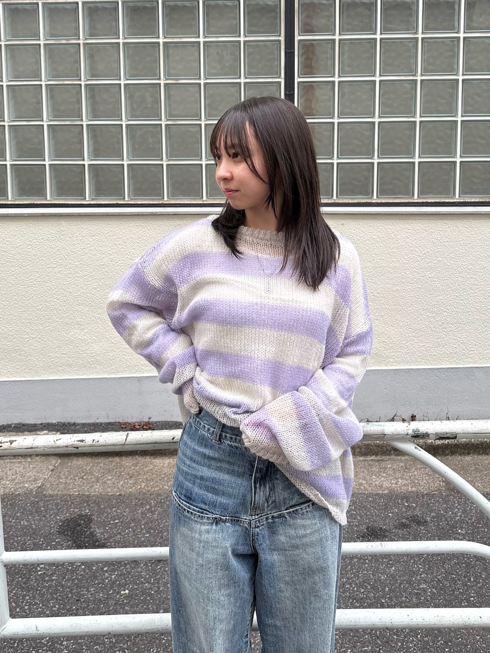 グレー系のニット/セーター、ブルー系のデニムパンツを着用したレディースの春コーディネートの2枚目の写真