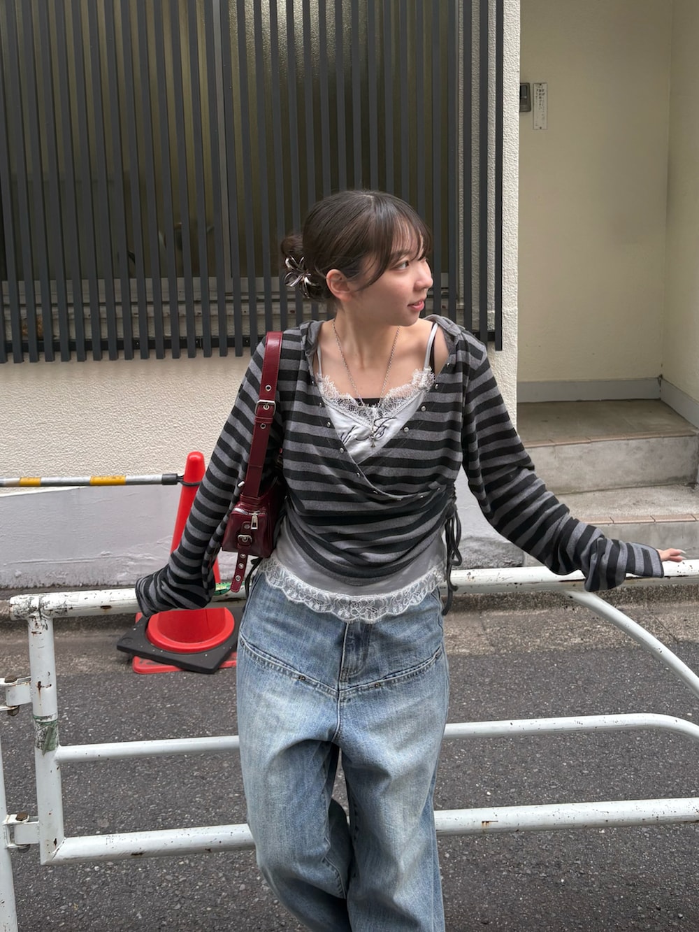 グレー系のパーカー、グレー系のキャミソール、レッド系のショルダーバッグを着用したレディースの春コーディネートの2枚目の写真