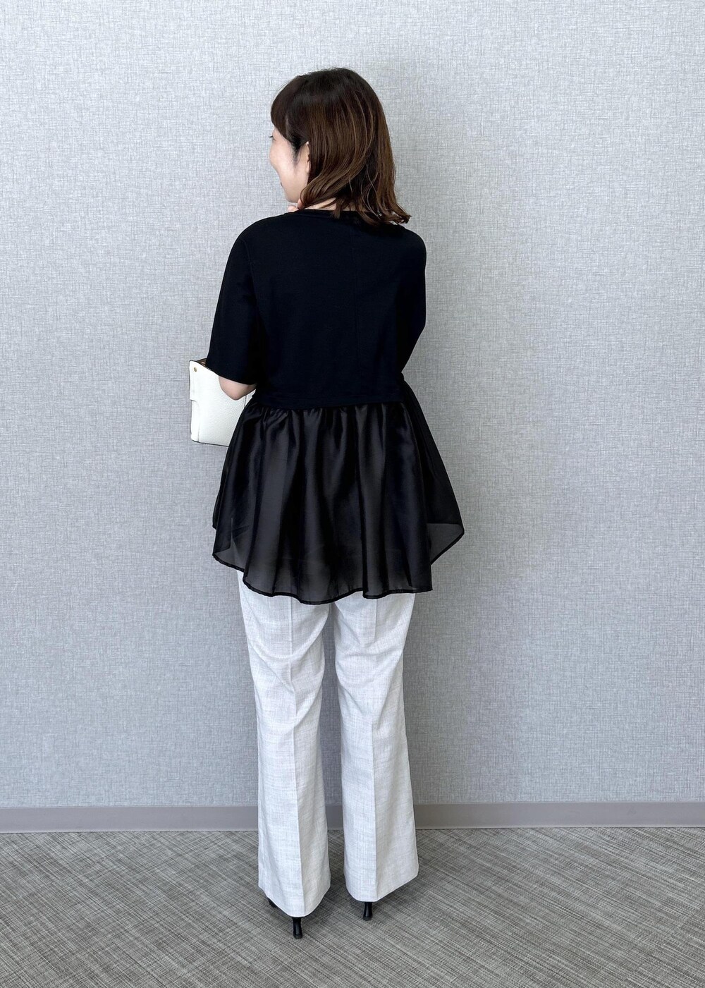 ホワイト系のハンドバッグ、ベージュ系のその他パンツ、ブラック系のTシャツ/カットソーを着用したレディースの夏コーディネートの4枚目の写真
