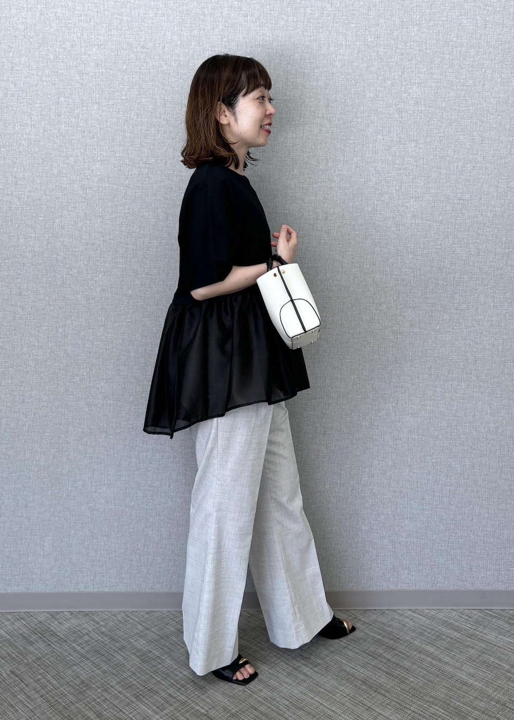 ホワイト系のハンドバッグ、ベージュ系のその他パンツ、ブラック系のTシャツ/カットソーを着用したレディースの夏コーディネートの2枚目の写真