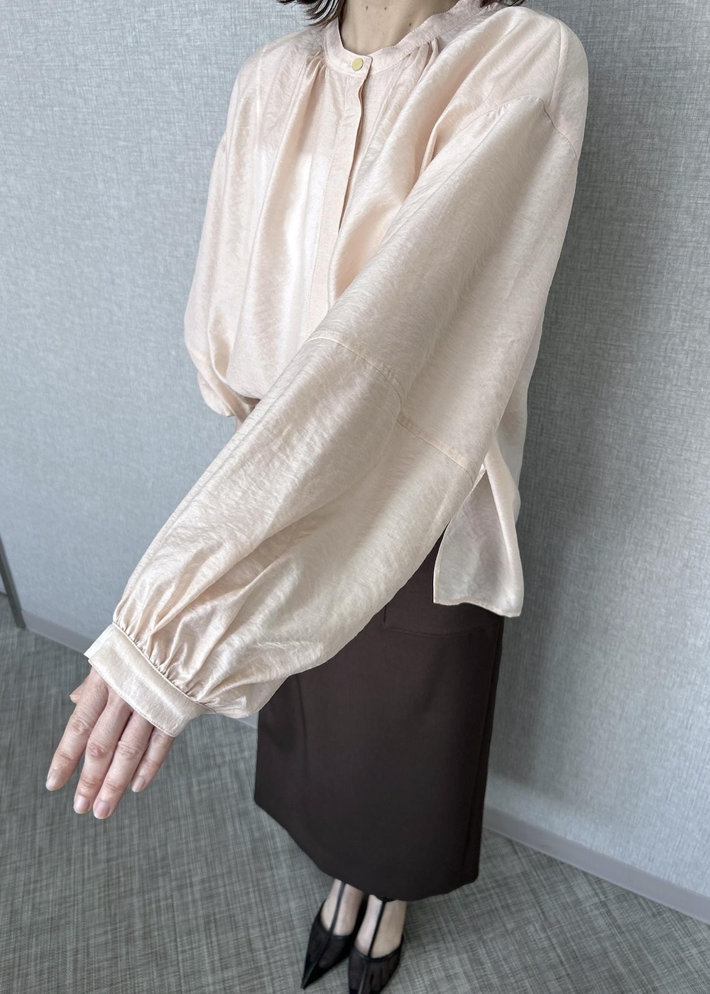 ブラック系のパンプス、ベージュ系のハンドバッグ、ブラウン系のスカートを着用したレディースの冬コーディネートの6枚目の写真