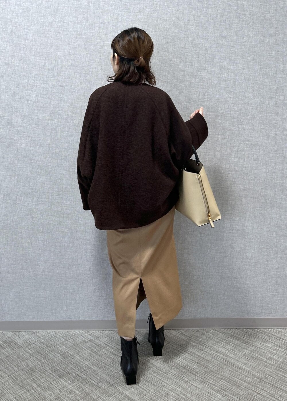 ベージュ系のトートバッグ、ブラック系のブーツ、ベージュ系のスカートを着用したレディースの秋コーディネートの6枚目の写真