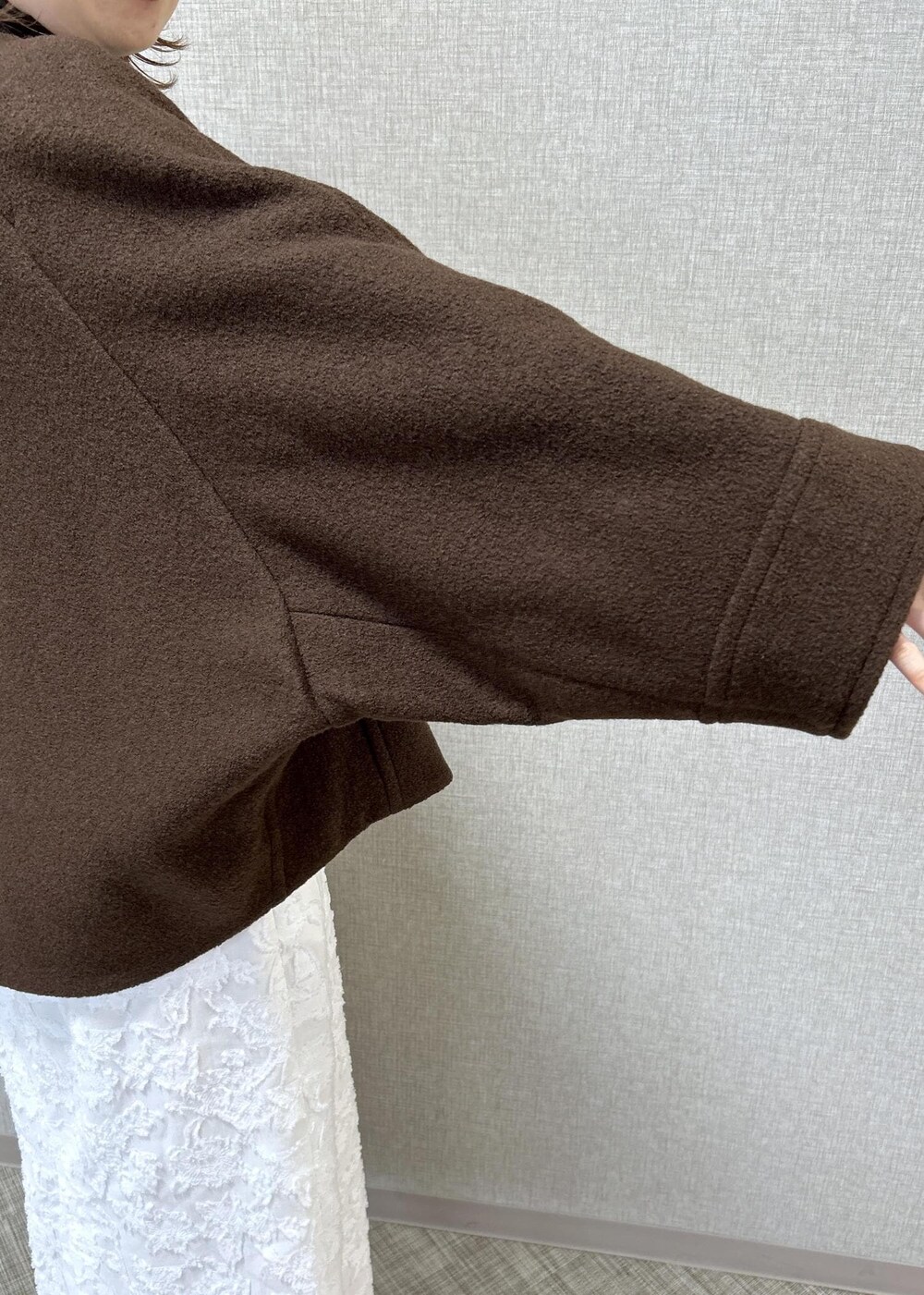 ベージュ系のトートバッグ、ブラック系のブーツ、ホワイト系のスカートを着用したレディースの秋コーディネートの6枚目の写真