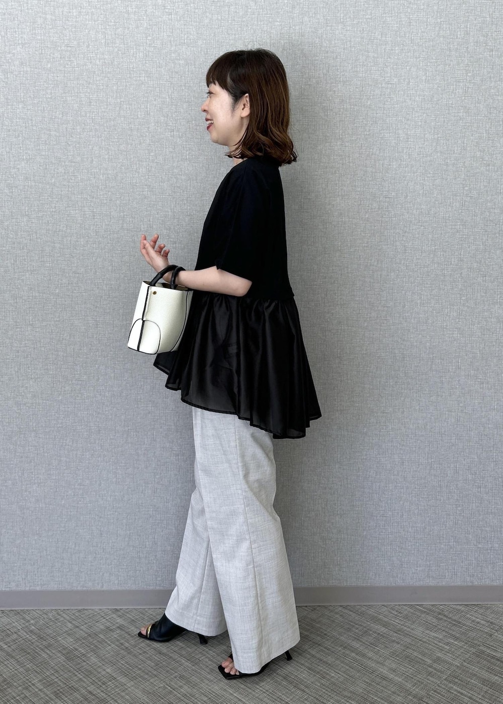 ホワイト系のハンドバッグ、ベージュ系のその他パンツ、ブラック系のTシャツ/カットソーを着用したレディースの夏コーディネートの3枚目の写真